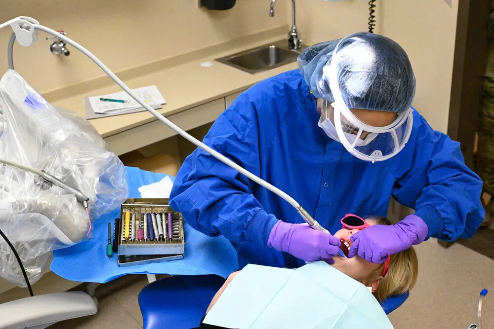 U.S. Air Force dental technician cleaning a child's teeth during Children's Dental Day at Ellsworth AFB, South Dakota, March 2023